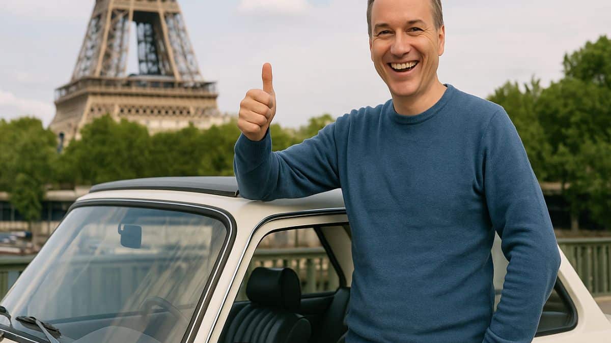 Un automobiliste heureux de la fin des zfe pose près de sa voiture ancienne avec la tour Eiffel en arrière-plan à Paris.