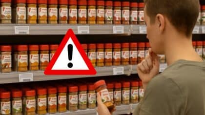 Une personne hésite devant un rayon rempli d’épices dans un supermarché Auchan en France.