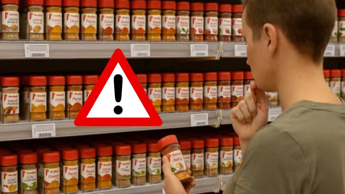 Une personne hésite devant un rayon rempli d’épices dans un supermarché Auchan en France.